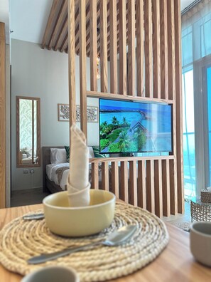 Une chambre moderne équipée d’un lit, d’un téléviseur diffusant des images de paysages tropicaux et d’une cloison en bois.