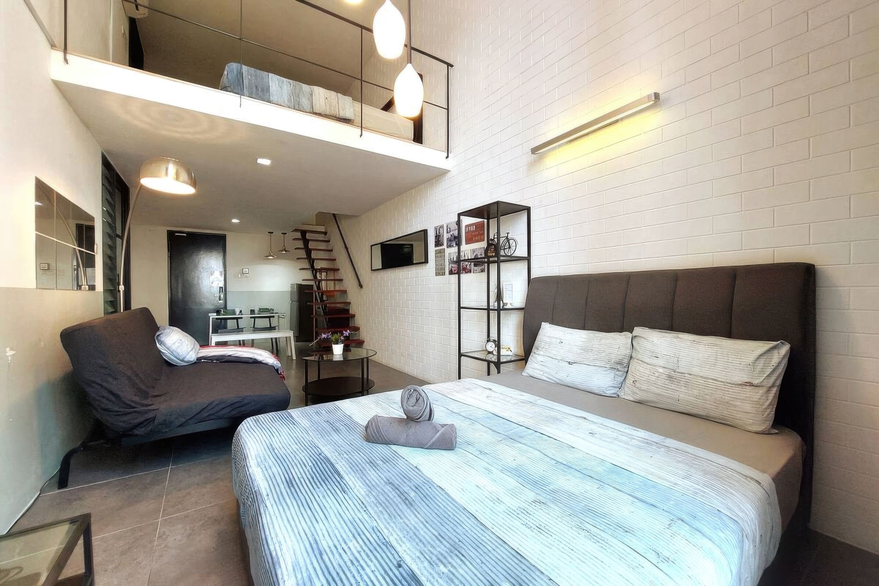 Ein modernes Schlafzimmer mit einem großen Bett, einer Couch, einem kleinen Tisch und einer Treppe, die zu einer oberen Ebene führt.