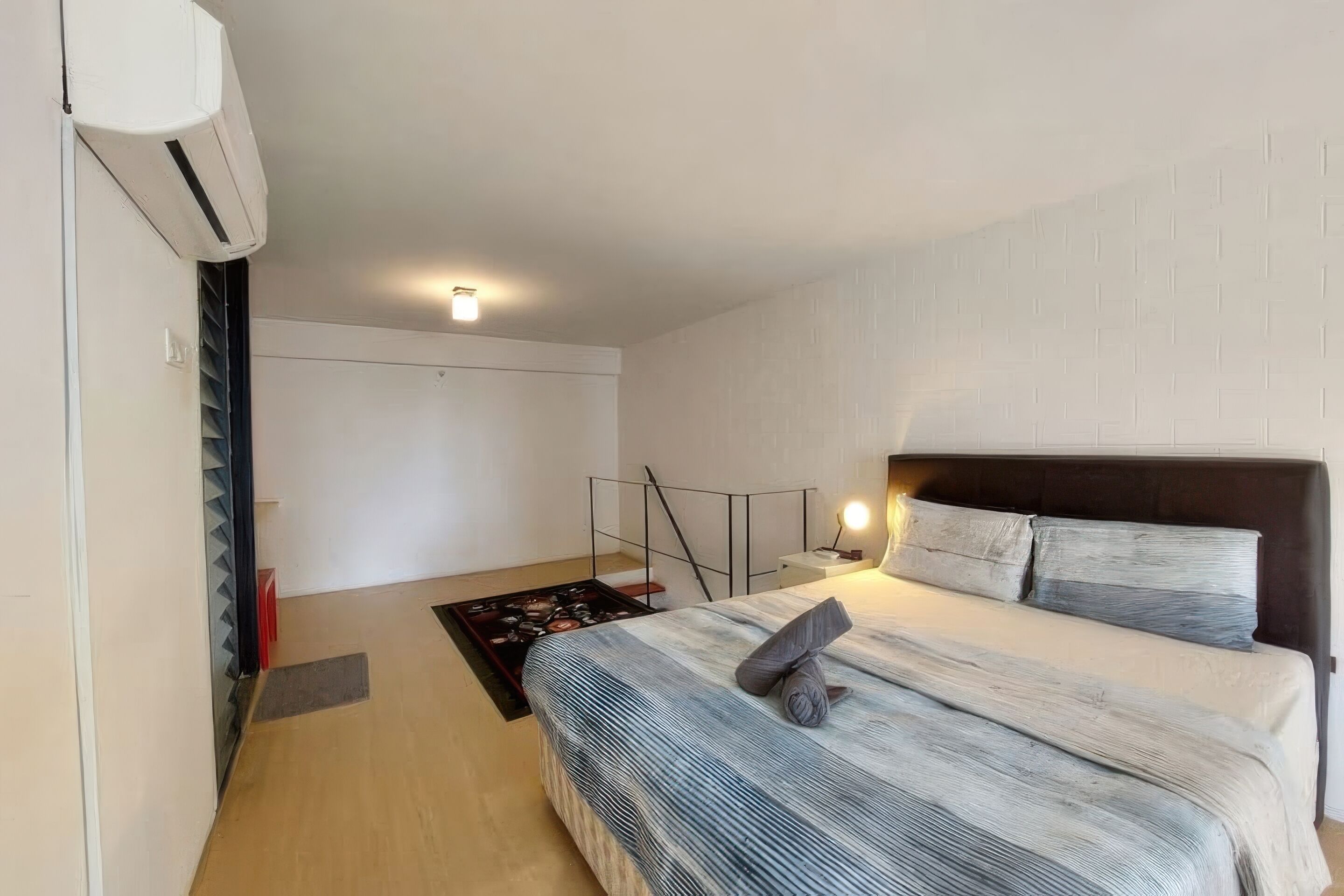 Une chambre à coucher comprenant un lit, une table de chevet, une lampe et un appareil de climatisation.