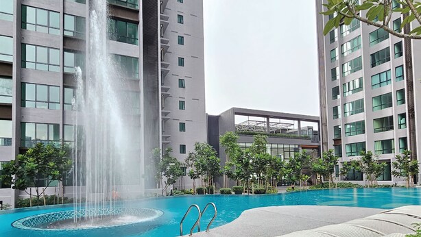 Una piscina con fuente, rodeada de edificios modernos y vegetación.