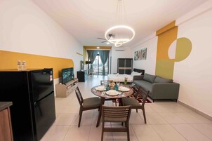 Una sala de estar moderna con comedor, un sofá, un televisor y un ventilador de techo.