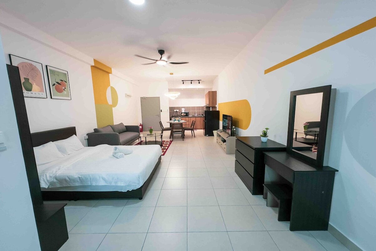 Une chambre d’hôtel moderne avec un lit, un canapé, un bureau et, au fond, un coin repas.
