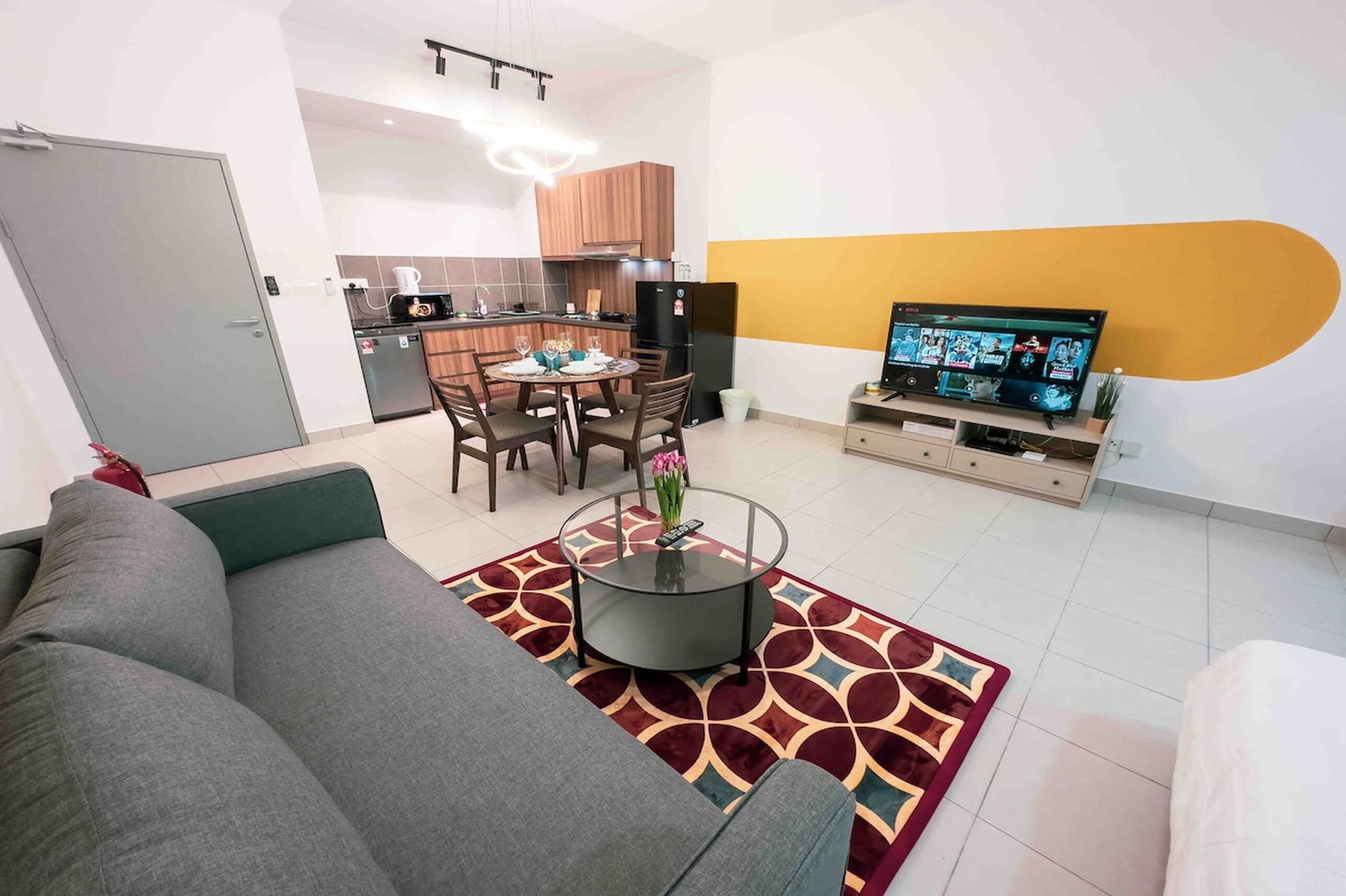 A modern living room with a grey sofa, a coffee table, and a dining area with a table and chairs.
