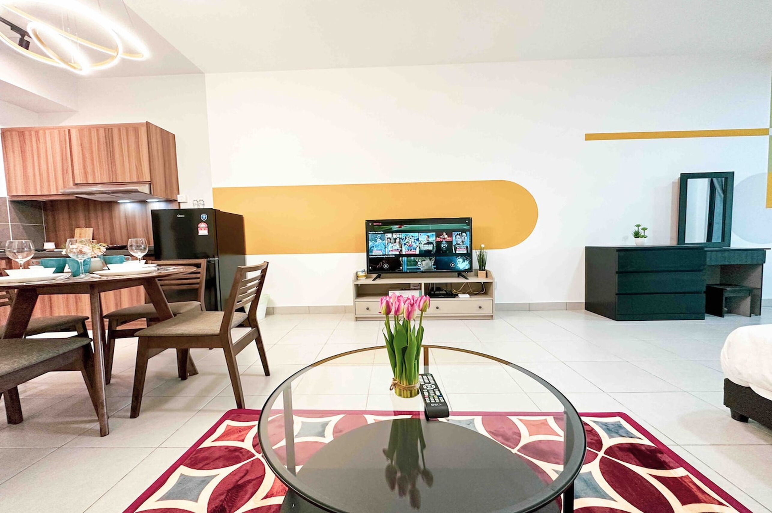 Ein modernes Wohnzimmer mit Essbereich, Fernseher und einem Bett.
