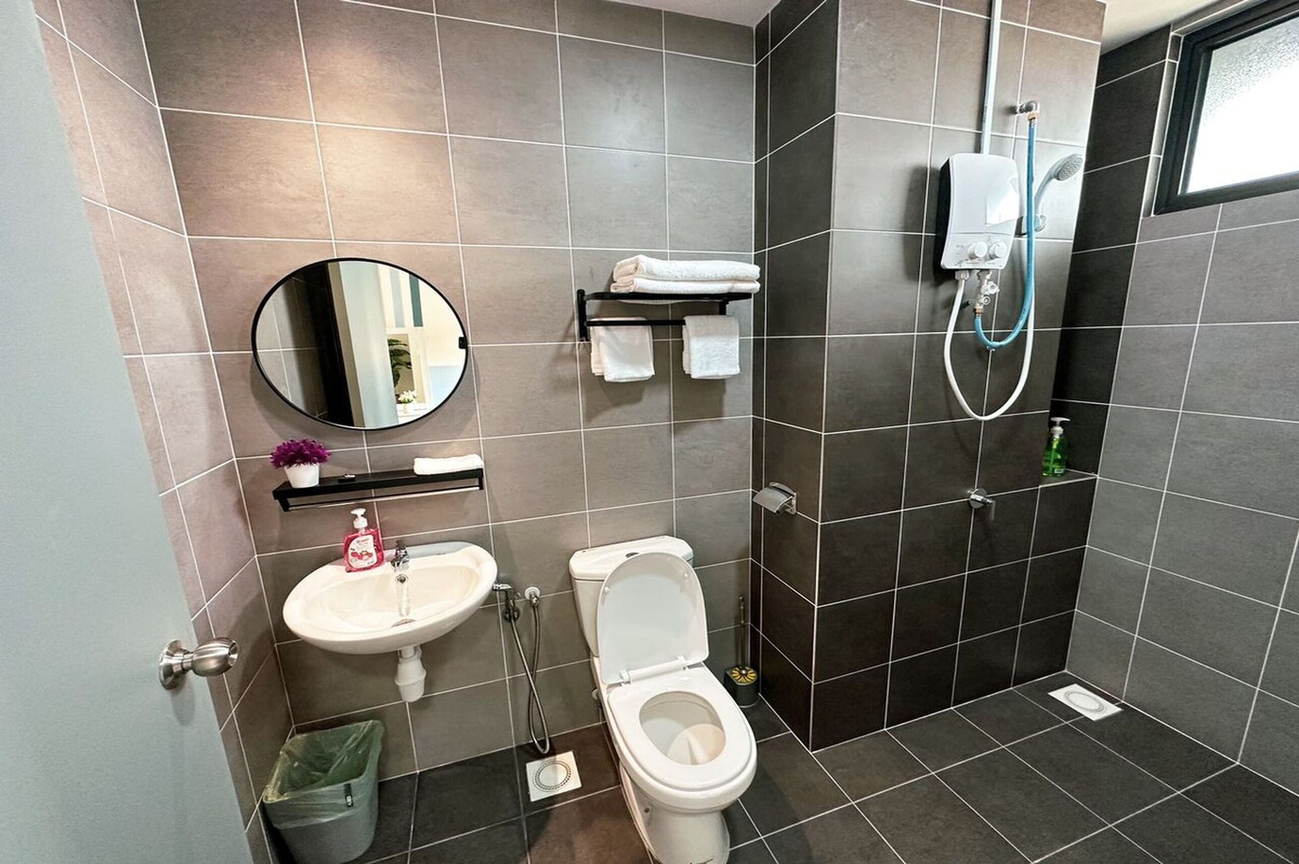 A modern bathroom with a white sink, toilet, and a shower with a handheld showerhead.