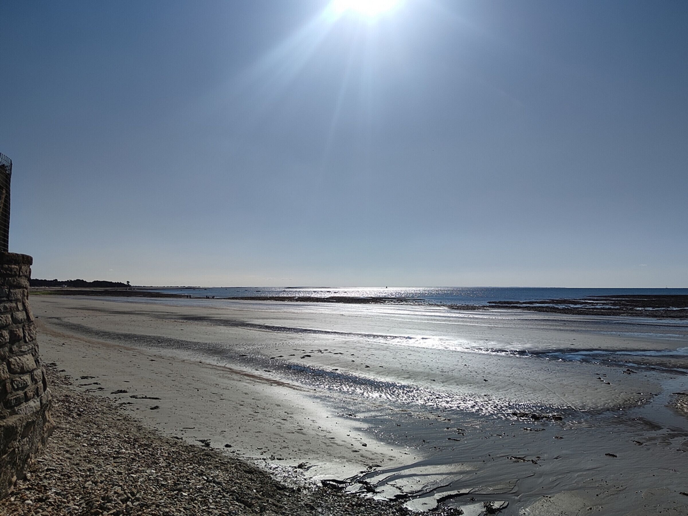 A beach with a clear sky and the sun shining.
