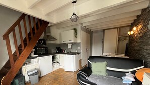 Ein kompakter Wohnraum mit einer Küche, einem Sofa, einem Esstisch und einer Treppe.