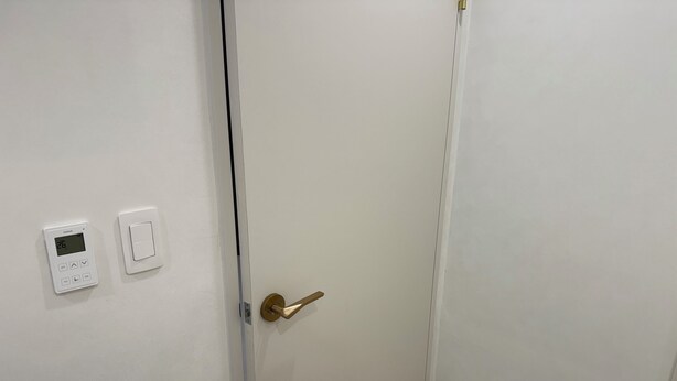 A closed door with a digital thermostat and a standard light switch on the wall. - Sweet Stay Seoul (Seoul)