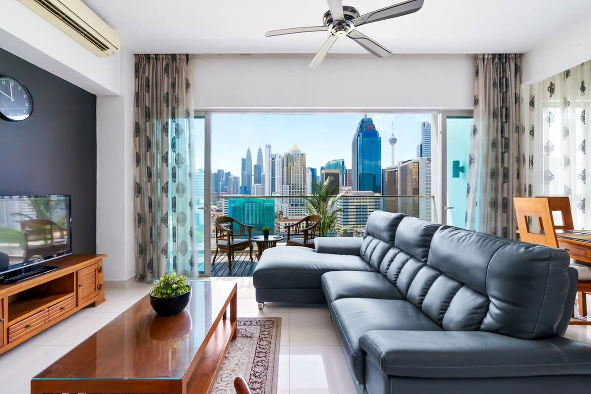 A modern living room with a sofa, TV, and a balcony with a city view.