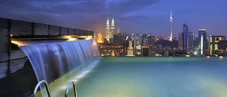 A rooftop infinity pool with a city skyline view, including prominent buildings and a tower.