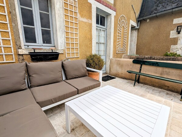 Een terras met een witte tafel en een bruine bank.