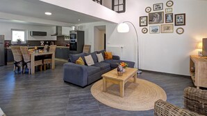 A modern living room with a grey sofa, a wooden coffee table, and a dining area with wicker chairs. - Spacious and modern cottage with terrace in the heart of nature (Saint-Appolinard)