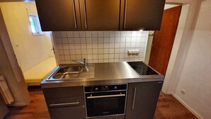 Una cocina compacta con un lavamanos de acero inoxidable, un horno y una estufa.