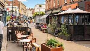 Een straat met terrasjes van een restaurant genaamd 'Bravas'.