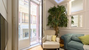 A living room with a sofa, armchair, and a large plant.