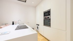 A modern kitchen with a central island, built-in oven, and washing machine.