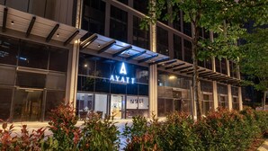 Ett modernt hotell med en fasad av glas, en framträdande skylt i form av bokstaven ”A” och en väl upplyst entré.