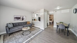 A modern living room with a grey sectional sofa, a round coffee table, and a dining area with a wooden table and chairs. - Beautiful 1Bd/1Bd Apartment in Dallas (Dallas)