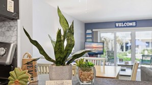 Un comptoir de cuisine avec une plante en pot, une tasse à café et un petit panneau.