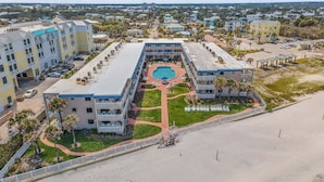 Un complexe hôtelier doté d’une piscine centrale, de plusieurs bâtiments et d’un espace de plage.