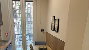 A compact kitchen with a dining area, a window with a view of buildings, and a small table with chairs. - Masonber Style & Comfort in the Center of Rome: (Roma)