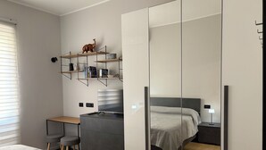 A modern bedroom with a bed, a desk, a wardrobe, and shelves with books and a decorative item. - Masonber Style & Comfort in the Center of Rome: (Roma)
