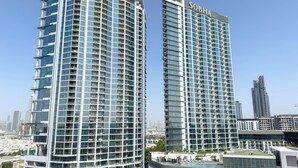 Two high-rise buildings with a modern architectural design, featuring extensive glass facades and multiple balconies. - Chic Meydan Apt with Balcony and City & Pool Views-1012 (Dubai)