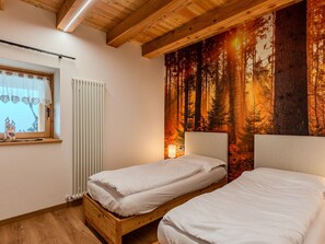 A bedroom with two single beds, a window with a curtain, and a forest-themed wall tapestry. - Cosy apartment in villa for 4 guests with WIFI, TV, patio and panoramic view (Rumo)