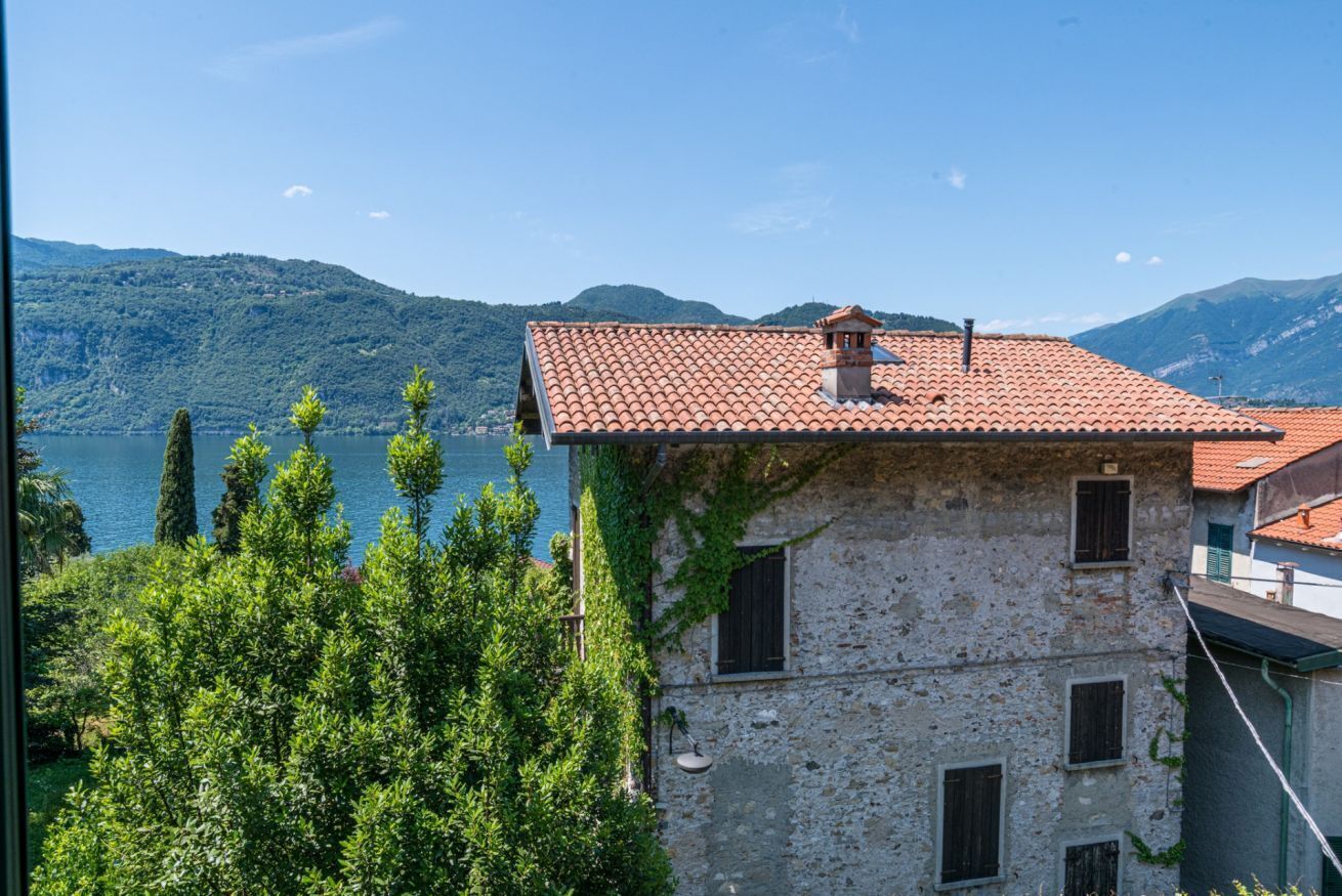 A stone building with a red-tiled roof, a small chimney, and a window.
