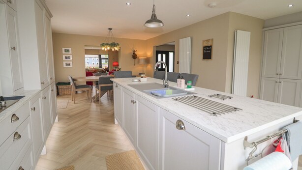 A spacious kitchen with a marble countertop, a built-in sink, and a dining area with a table and chairs. - Clarmes House (Limavady)