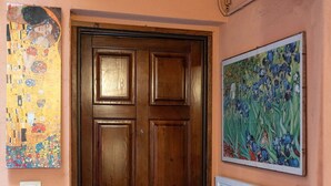 Une porte en bois, dotée d’une poignée, et de part et d’autre de laquelle sont accrochées deux peintures au mur.