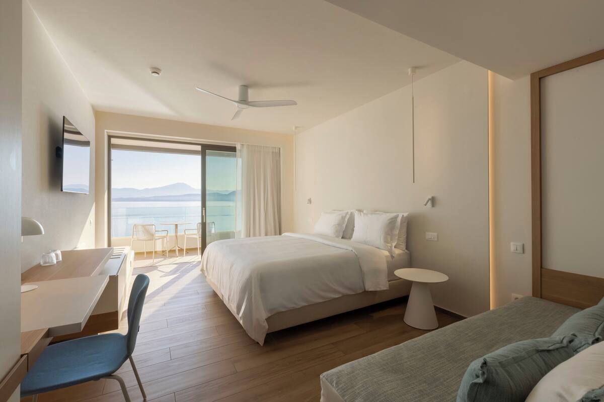 Ein modernes Hotelzimmer mit Bett, Schreibtisch, Stuhl und einem kleinen Tisch.