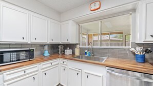 A kitchen with white cabinets, a microwave, a toaster, and a sink.