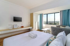 Una camera d'albergo con un letto, una televisione, un tavolino e un divano.