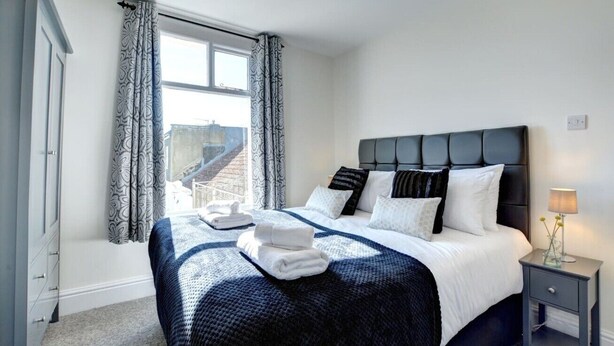 Ein Schlafzimmer mit Bett, Nachttisch und einem Fenster mit Vorhängen.