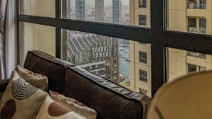 Une pièce dotée d’une grande fenêtre donnant sur un panorama urbain, où l’on peut notamment apercevoir les tours Sparkle.