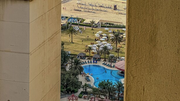 Une vue d’un complexe hôtelier en bord de mer, avec une piscine, des parasols et une jetée.