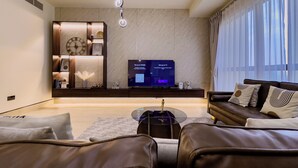 Un salon moderne avec un téléviseur à écran plat, une horloge et une étagère décorative.
