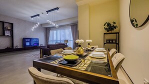 Un coin repas avec une table en verre, des chaises et un téléviseur en arrière-plan.