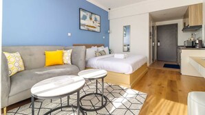 A modern, compact living space with a sofa, a bed, a small kitchen area, and a dining table. - Upperhill View Palace Apartment (Nairobi)