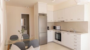 Una cocina moderna con armarios blancos, un refrigerador de acero inoxidable, un microondas y un lavamanos.