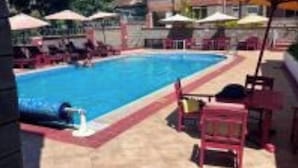 Ein Pool mit Liegestühlen und Sonnenschirmen, umgeben von einem mehrstöckigen Gebäude.