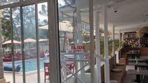 Ein modernes Hotelinterieur mit großen Schiebegläsern, die zu einem Poolbereich führen.