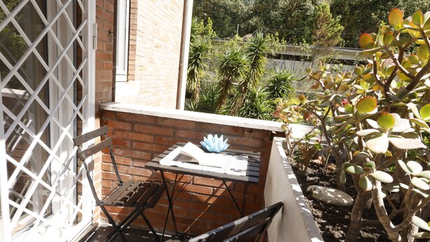 Un pati amb taula, cadires i un petit espai jardí amb plantes.