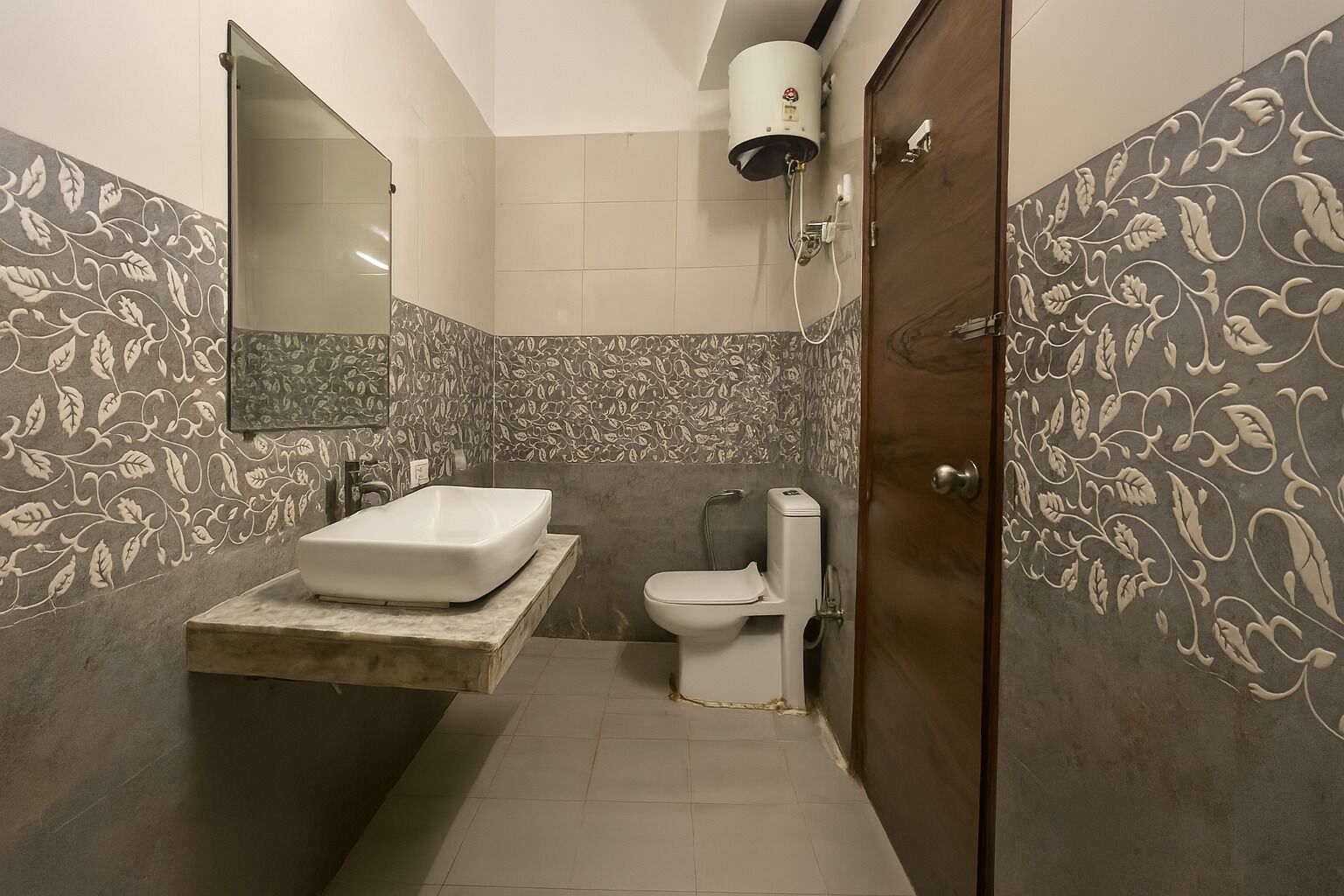 A bathroom with a large mirror, a sink, a toilet, and a shower.
