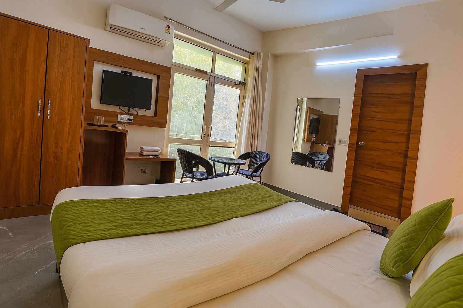 Una habitación de hotel con cama, escritorio, silla, televisor y armario.