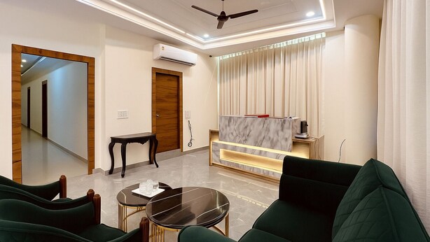 A modern living room with a sofa set, a coffee table, a TV, and a reception desk. - Hotel Yash Regency - Managed by JMD Group (New Delhi)