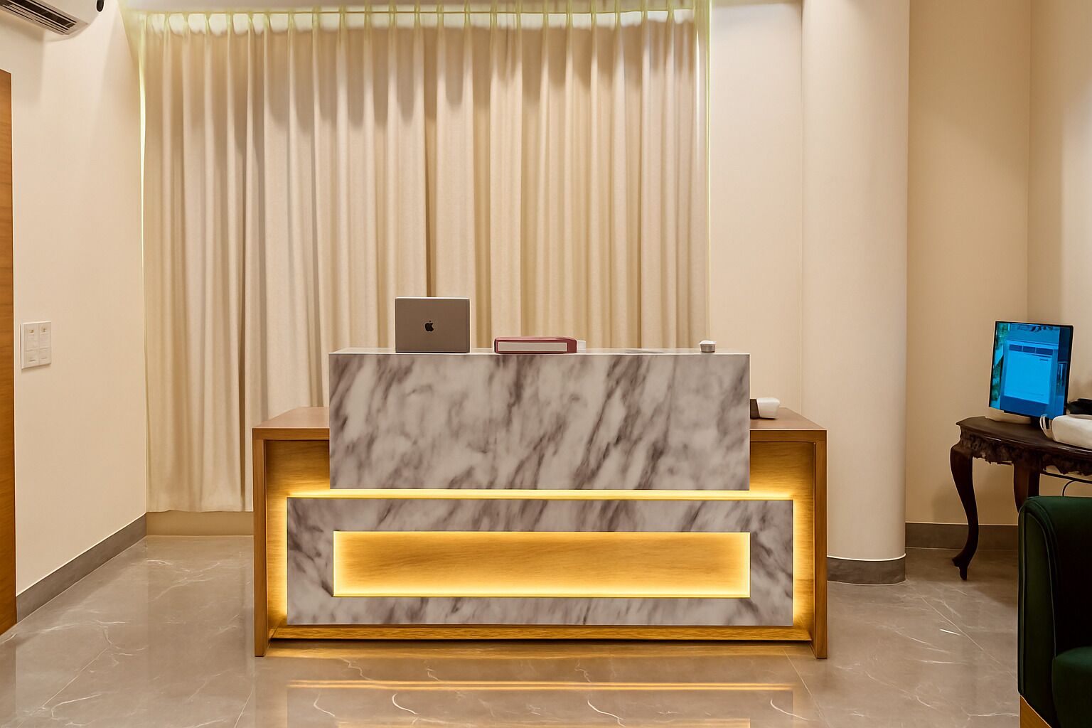 A reception desk with a marble top, a laptop, and a book on it. There is a computer monitor to the right.