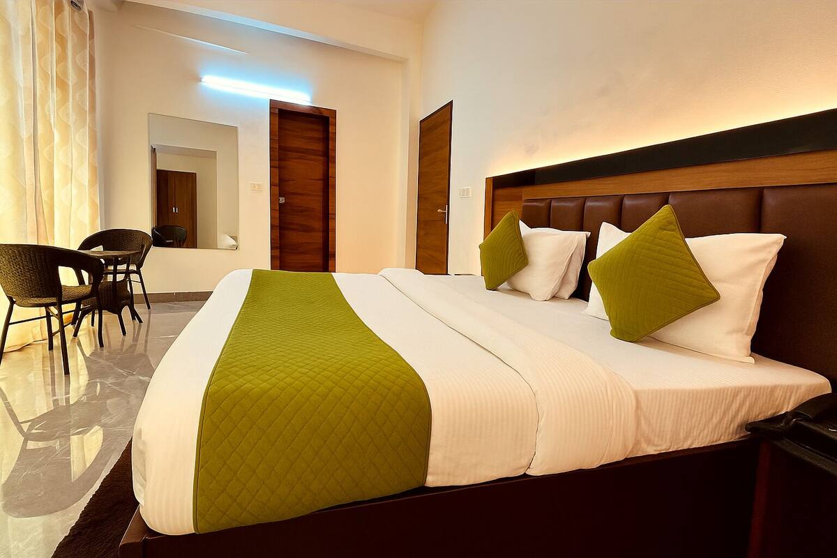 A hotel room with a large bed, a wooden headboard, and a seating area with chairs.