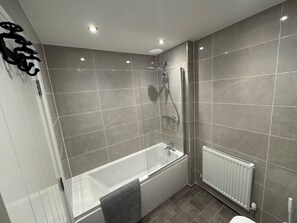 A modern bathroom with a glass-enclosed shower, a standalone bathtub, and a white radiator. - Lower Townhouse  Exeter (Devon)